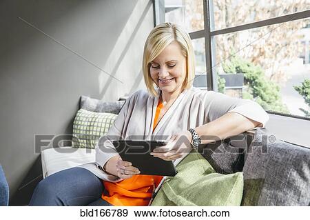 Stock Photo - Caucasian businesswoman using digital tablet in office lobby. Fotosearch