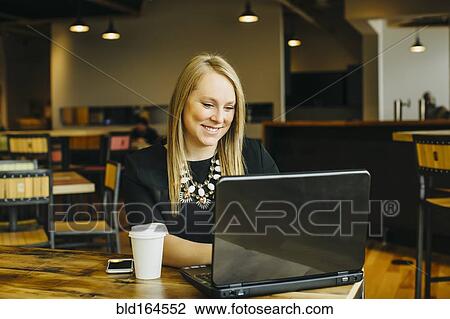 Stock Image - Caucasian businesswoman working on laptop in cafe. Fotosearch
