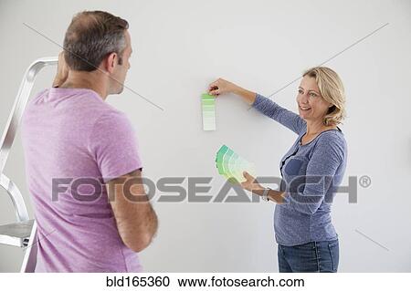 Stock Image - Caucasian couple examining color swatches in new home. Fotosearch