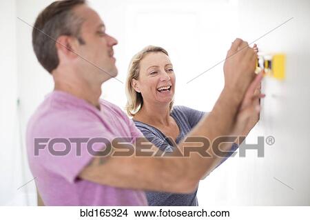 Picture - Caucasian couple using level in new home. Fotosearch