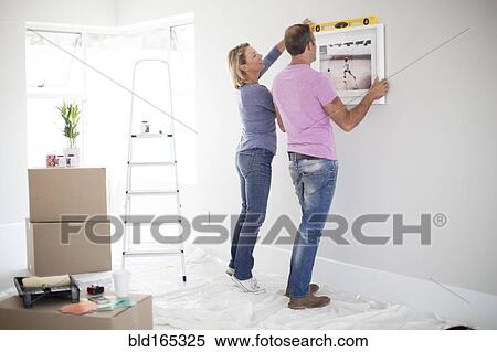 Stock Photography - Caucasian couple using level in new home. Fotosearch