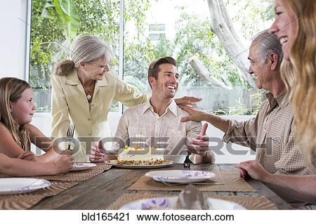 Stock Image - Caucasian family celebrating birthday at table. Fotosearch