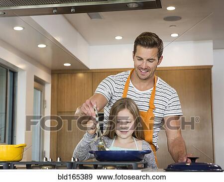 Stock Photo - Caucasian father and daughter cooking in kitchen. Fotosearch