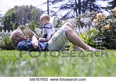 Stock Image - Caucasian father and son playing in grass. Fotosearch