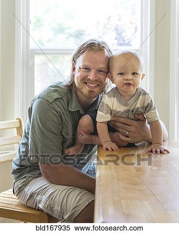 Stock Photography - Caucasian father and son smiling at table. Fotosearch