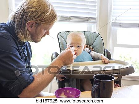 Caucasian father feeding son in high chair View Large Photo Image Stock Photography - Caucasian father feeding son in high chair. Fotosearch