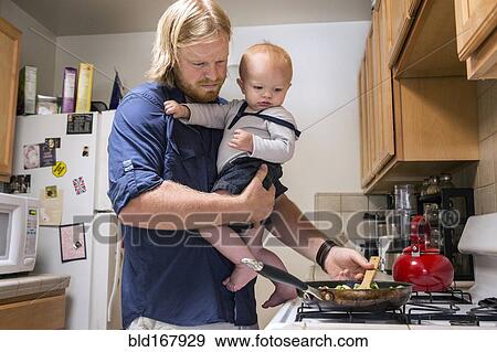 Stock Photo - Caucasian father holding son and cooking. Fotosearch