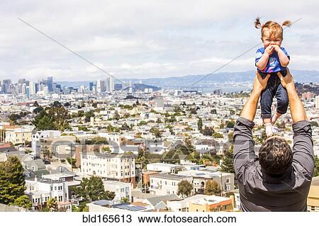 Stock Image - Caucasian father lifting daughter over San Francisco cityscape, California, United States. Fotosearch