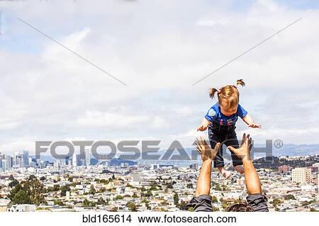 Picture - Caucasian father tossing daughter over San Francisco cityscape, California, United States. Fotosearch