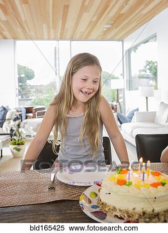Stock Photography - Caucasian girl admiring birthday cake at party. Fotosearch