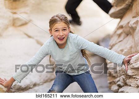 Stock Image - Caucasian girl exploring desert rock formations. Fotosearch