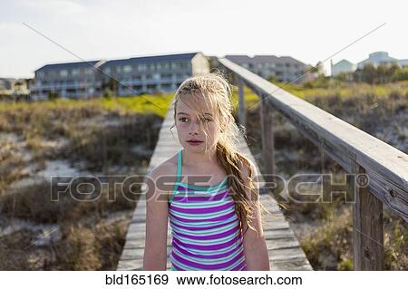 Stock Photo - Caucasian girl on wooden walkway on beach. Fotosearch