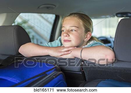 Stock Image - Caucasian girl sitting in car back seat on road trip. Fotosearch