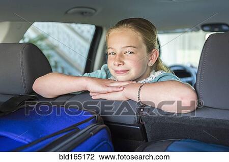 Stock Image - Caucasian girl sitting in car back seat on road trip. Fotosearch