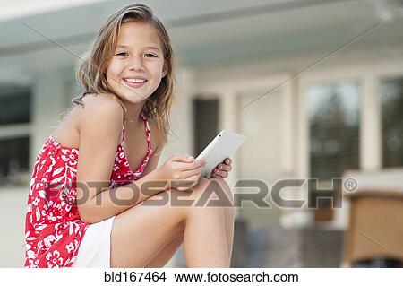 Picture - Caucasian girl using digital tablet outdoors. Fotosearch