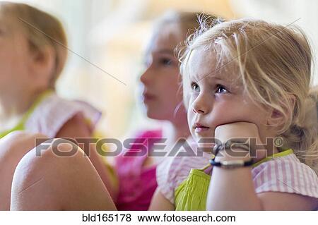 Stock Photo - Caucasian girls watching television in armchair. Fotosearch