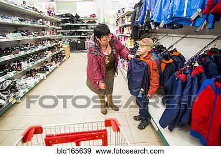 Stock Photo - Caucasian grandmother and grandson shopping in clothing store. Fotosearch