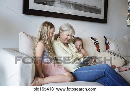 Caucasian grandmother and granddaughters using digital tablet on sofa View Large Photo Image Stock Image - Caucasian grandmother and granddaughters using digital tablet on sofa. Fotosearch