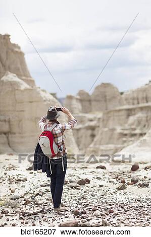 Stock Photo - Caucasian hiker photographing desert rock formations. Fotosearch