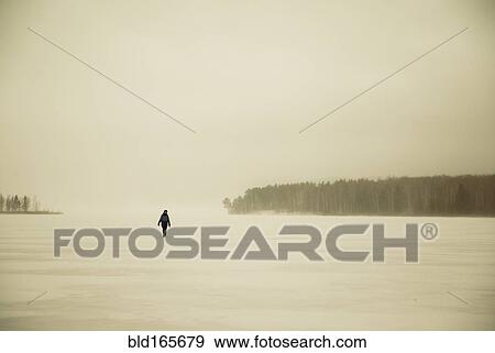 Stock Photo - Caucasian hiker walking in snowy remote field. Fotosearch