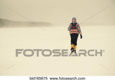 Stock Photography - Caucasian hiker walking in snowy remote field. Fotosearch