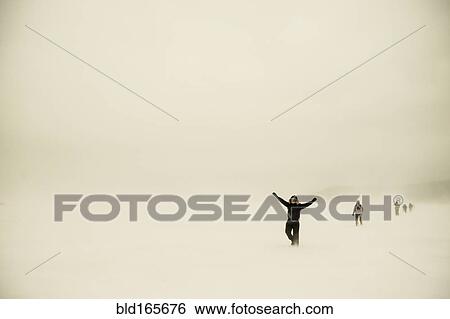 Stock Photograph - Caucasian hikers walking in snowy remote field. Fotosearch