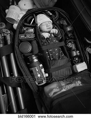Stock Image - Caucasian infant packed into camera bag. Fotosearch