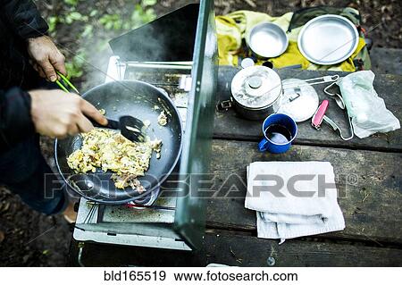 Caucasian man cooking eggs at campsite View Large Photo Image Stock Photo - Caucasian man cooking eggs at campsite. Fotosearch