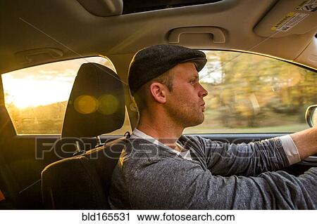 Caucasian man driving car at sunset View Large Photo Image Stock Image - Caucasian man driving car at sunset. Fotosearch