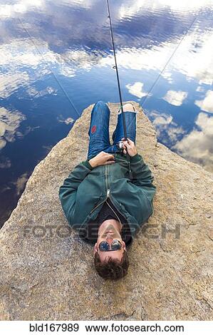 Stock Photo - Caucasian man fishing in remote lake. Fotosearch