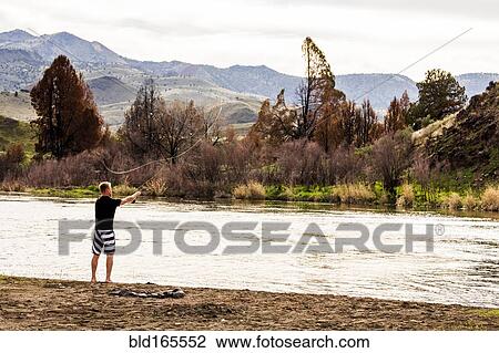 Stock Image - Caucasian man fishing in remote river, Painted Hills, Oregon, United States. Fotosearch