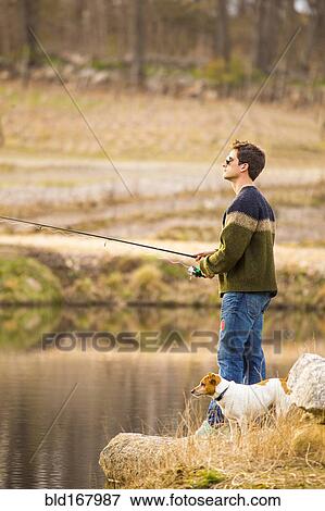 Caucasian man fishing with dog in remote lake View Large Photo Image Stock Photo - Caucasian man fishing with dog in remote lake. Fotosearch