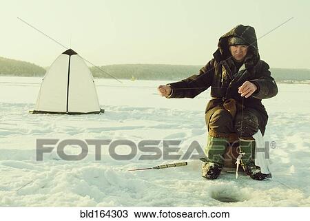 Caucasian man ice fishing on remote lake View Large Photo Image Stock Image - Caucasian man ice fishing on remote lake. Fotosearch