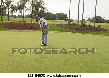 Stock Image - Caucasian man putting on golf course. Fotosearch