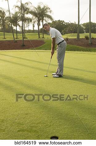 Stock Photo - Caucasian man putting on golf course. Fotosearch
