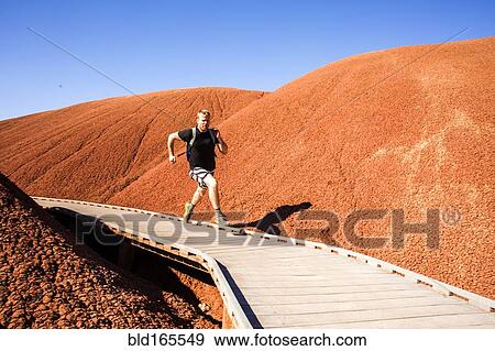 Stock Photo - Caucasian man running on walkway in desert hills. Fotosearch