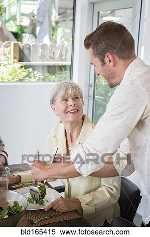 Caucasian man serving mother at table View Large Photo Image Stock Photography - Caucasian man serving mother at table. Fotosearch