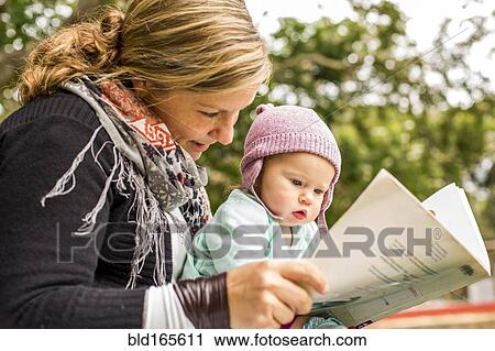 Caucasian mother and baby daughter reading in park View Large Photo Image Stock Image - Caucasian mother and baby daughter reading in park. Fotosearch