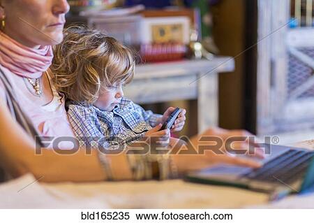 Stock Photography - Caucasian mother and baby son using technology. Fotosearch