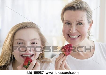 Stock Photo - Caucasian mother and daughter eating strawberries. Fotosearch