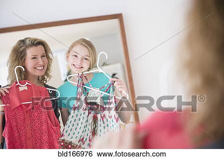 Stock Photograph - Caucasian mother and daughter examining shirts in mirror. Fotosearch