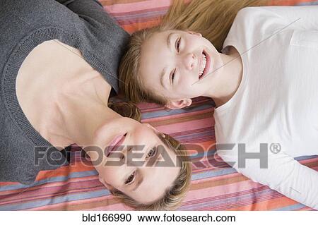Stock Image - Caucasian mother and daughter laying on blanket. Fotosearch