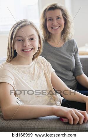 Stock Photo - Caucasian mother and daughter smiling on sofa. Fotosearch