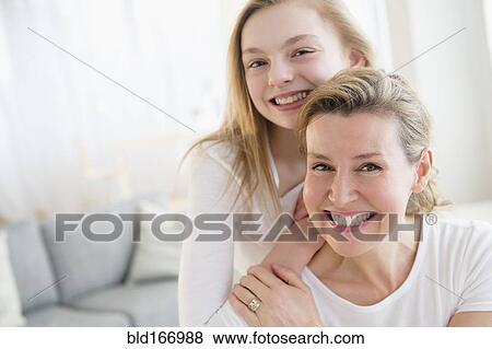 Stock Photo - Caucasian mother and daughter smiling in living room. Fotosearch