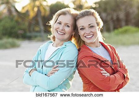 Stock Photo - Caucasian mother and daughter standing on beach. Fotosearch