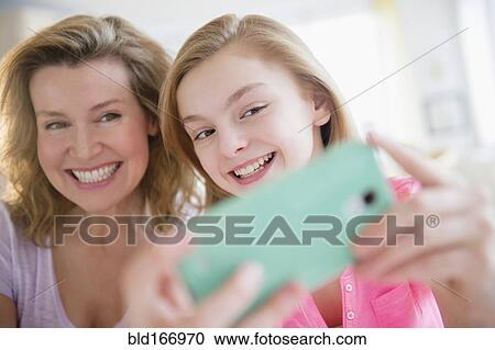 Stock Image - Caucasian mother and daughter taking selfies with cell phone. Fotosearch