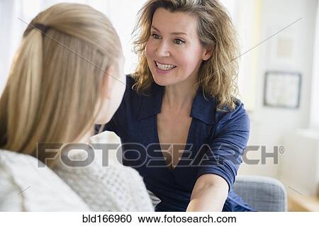 Stock Image - Caucasian mother and daughter talking on sofa. Fotosearch