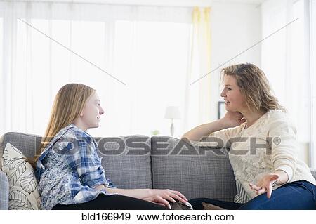 Stock Photo - Caucasian mother and daughter talking on sofa. Fotosearch