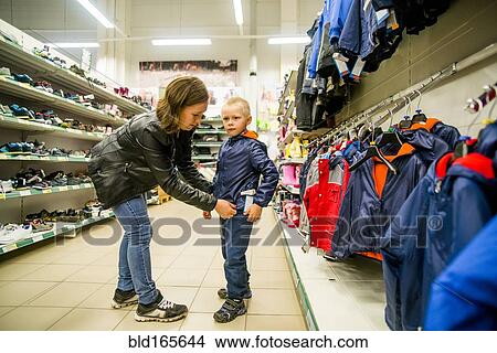 Picture - Caucasian mother and son shopping in clothing store. Fotosearch