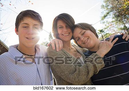 Stock Image - Caucasian mother and sons hugging outdoors. Fotosearch